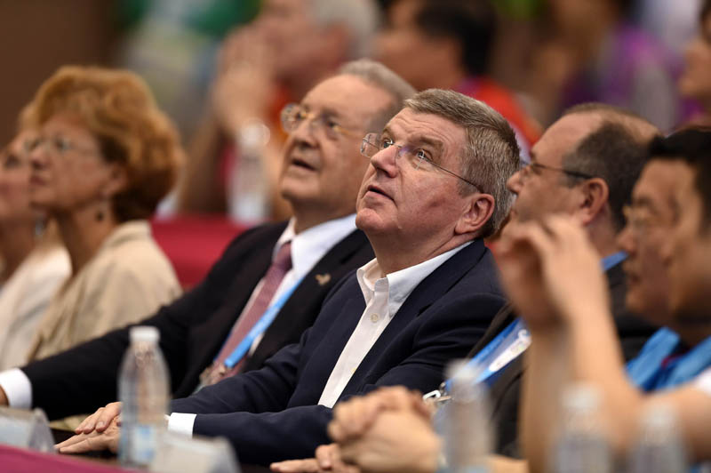 国际奥委会主席巴赫（中）在观看屏幕上显示的选手成绩