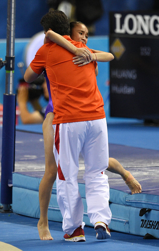 中国选手黄慧丹(右)在高低杠比赛后与教练王群策拥抱.