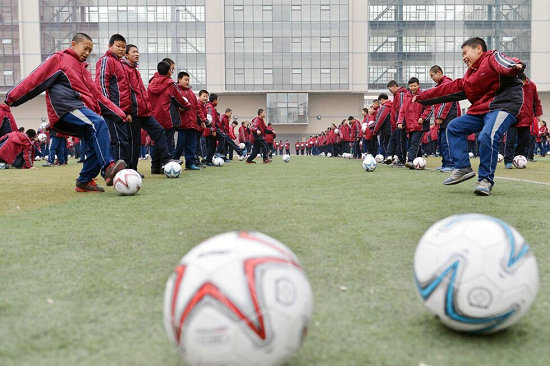 2014年12月9日世界足球日，呼和浩特市第三十五中學學生做足球游戲。      圖片：新華社發