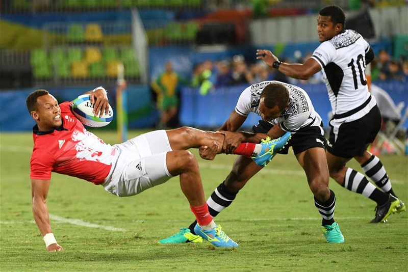 巴西當地時間8月11日晚上，在2016年裡約奧運會男子橄欖球決賽中，斐濟隊以43比7戰勝英國隊，奪得金牌。圖為斐濟隊球員納卡拉瓦（右二）在決賽中防守英國進攻球員時拉住了對方的腿。新華社記者王毓國攝