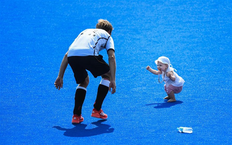 巴西當地時間8月18日，在2016年裡約奧運會男子曲棍球銅牌決賽中，德國隊和荷蘭隊在常規比賽時間戰成1比1平。最終，經過點球大戰德國隊以4比3戰勝荷蘭隊，獲得銅牌。圖為獲勝后的德國隊隊長菲爾斯特（左）在球場上與女兒嬉戲。新華社記者劉大偉攝