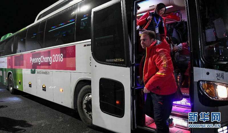 2月5日，中国冰壶队总教练、加拿大人马塞尔（前）走下大巴准备进驻运动员村。