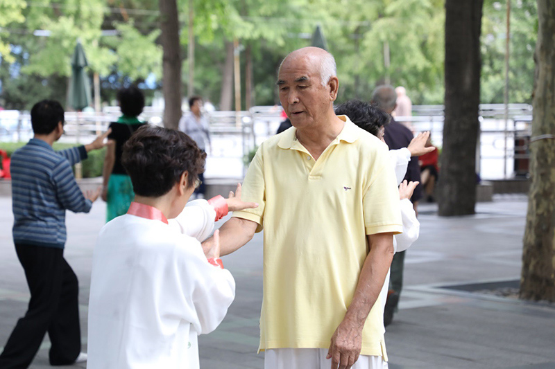 84歲的王老師，是前任太極拳輔導站站長，1961年開始學習太極拳，可謂太極拳文化中的元老。王老師正在對學員的動作進行指導，現在依舊每天堅持練習太極拳