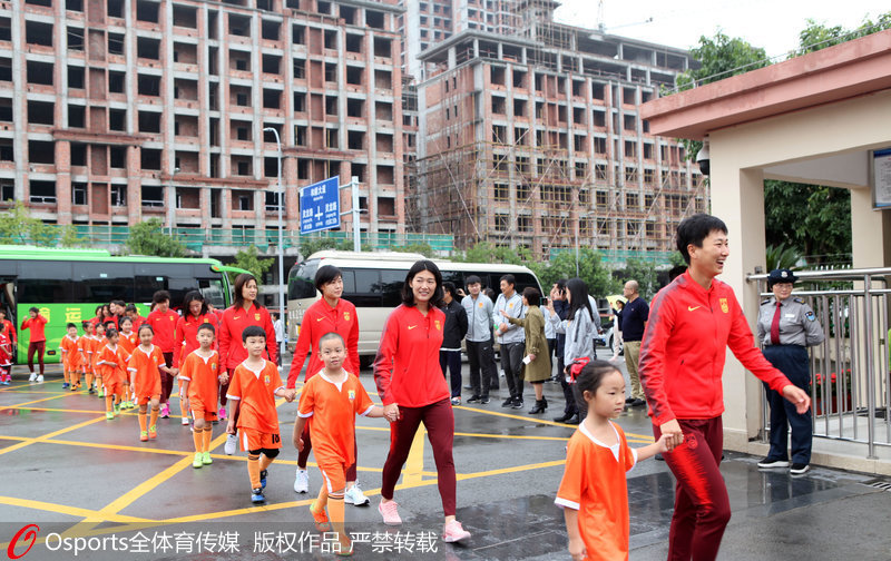 小隊員手牽女足姑娘的手走進校園。