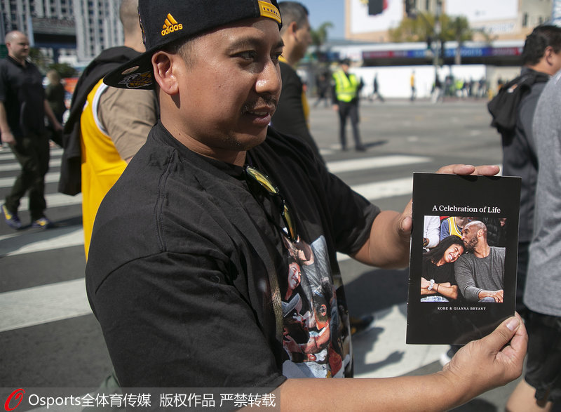 一位球迷展示斯台普斯中心為參加追思會球迷准備的紀念手冊