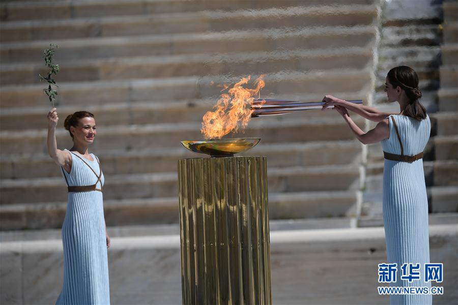 扮演最高女祭司的希臘女演員桑西·喬治烏（右）從聖火盆中點燃火炬。新華社發（阿裡斯·麥西尼攝）