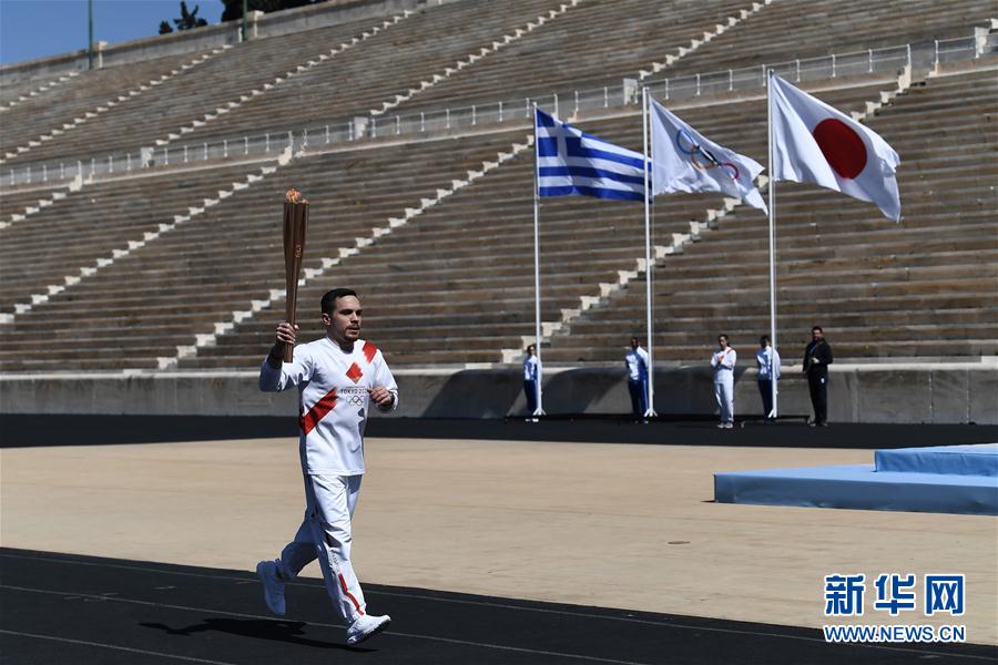 希臘藝術體操運動員埃萊夫塞裡奧斯·彼得羅尼亞斯手持聖火火炬跑入體育場。 新華社發（阿裡斯·麥西尼攝）